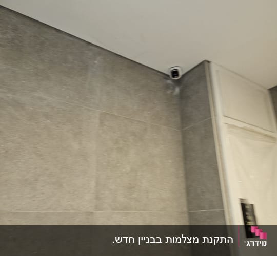 מצלמת אבטחה מותקנת בפינת תקרה על קיר אפור